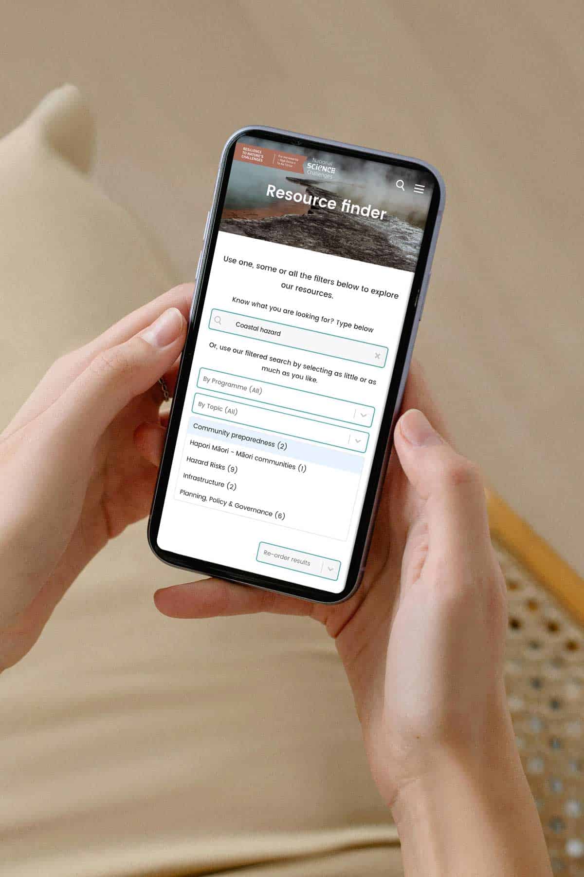 Hands holding a phone showing a resource finder page on a client website